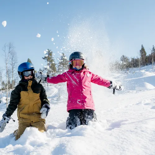 To barn som leker i snøen i skibakken